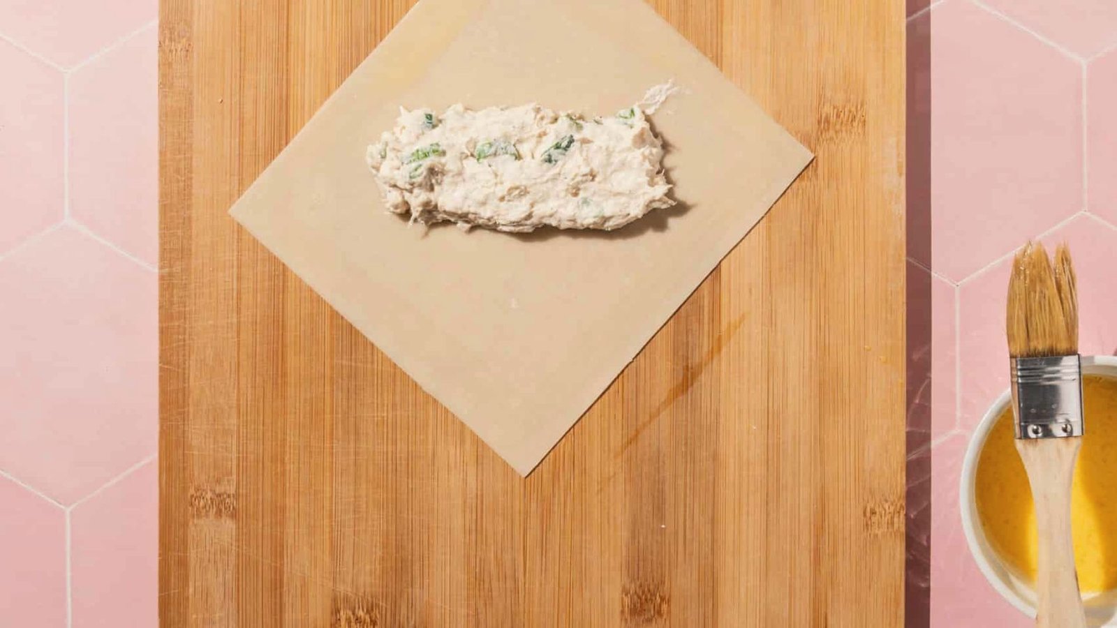 A wooden cutting board featuring crab egg rolls, part of a rolling station setup for meal preparation.