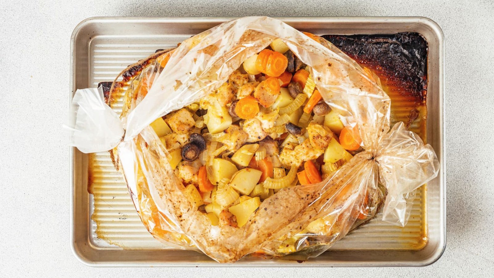 A pan containing a plastic-wrapped roast, suggesting the addition of vegetables for improved flavor.