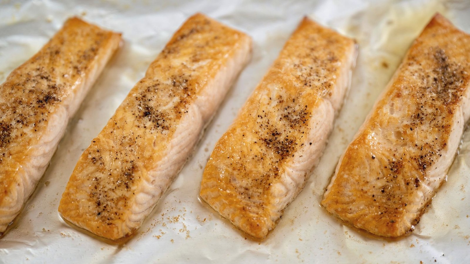 Four salmon fillets placed on a baking sheet, awaiting hibachi cooking instructions.