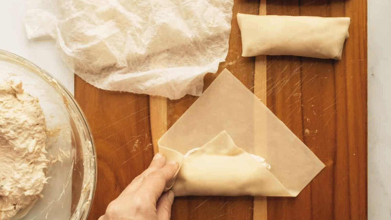 A person is shaping a dough ball in preparation for rolling egg rolls.